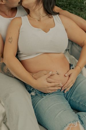 An intimate maternity photo showing hands cradling a baby bump.