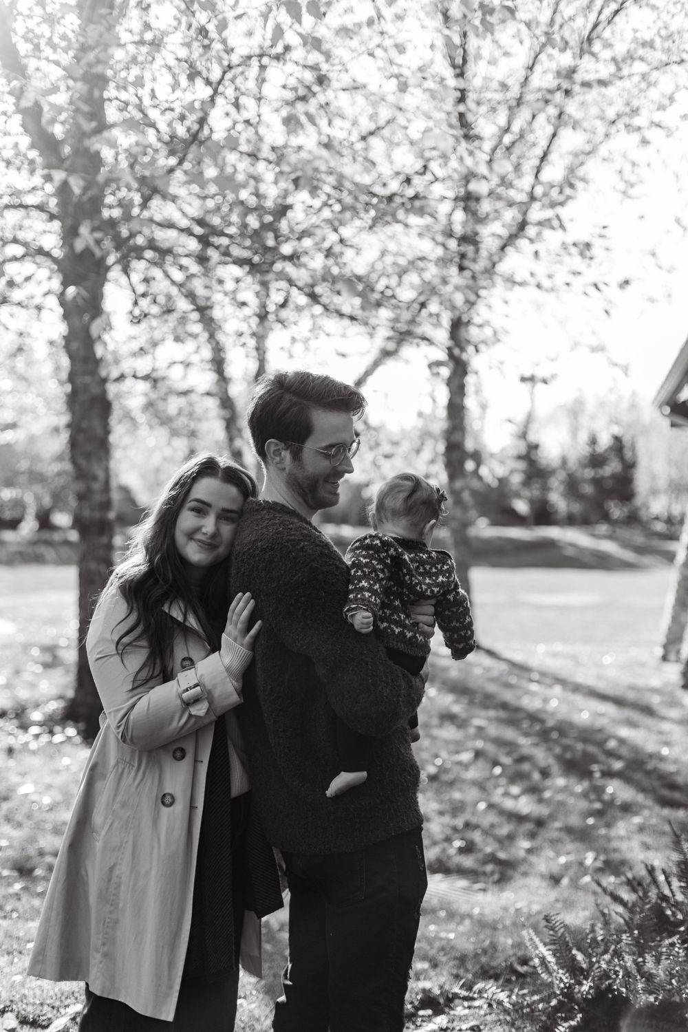 Family sharing an intimate moment outdoors in black and white photography.