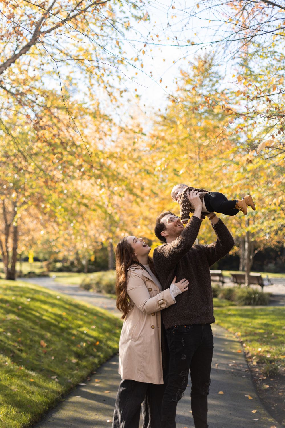 Family playing together on walkway surrounded by golden fall trees.