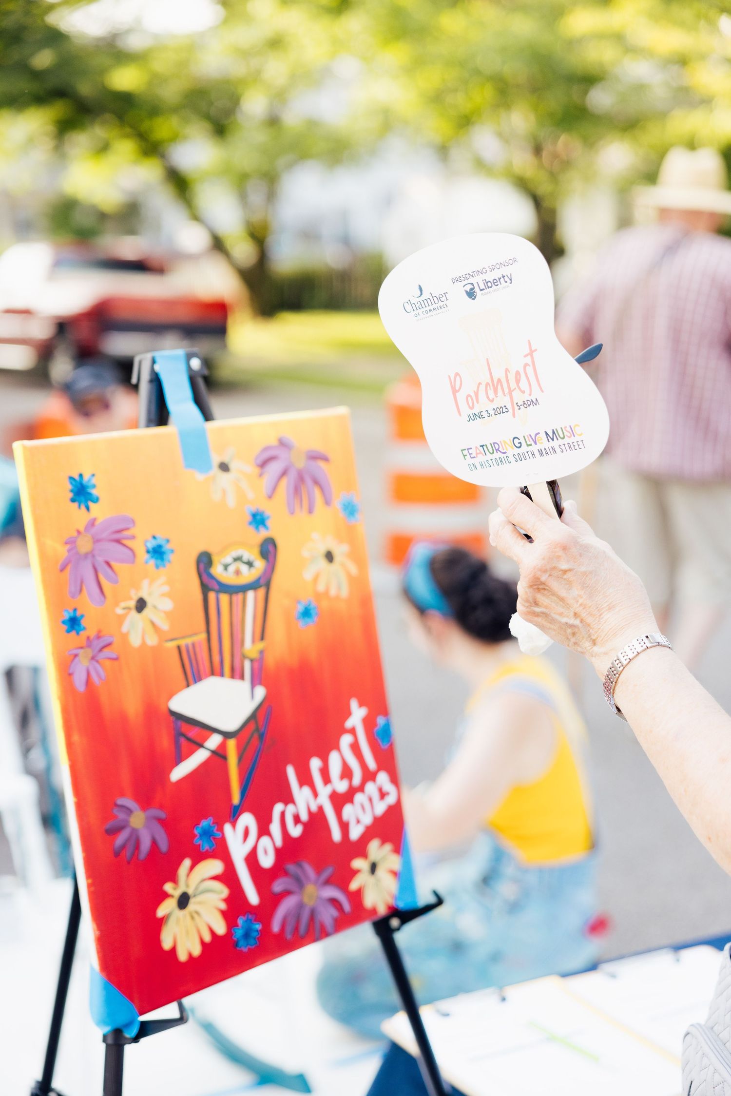 Colorful watercolor paintings with handwritten speech bubbles displayed at an outdoor event.