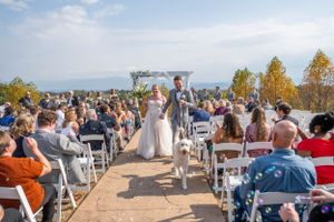 Newlyweds walking down the aisle while guests celebrate at an outdoor mountain wedding venue.
