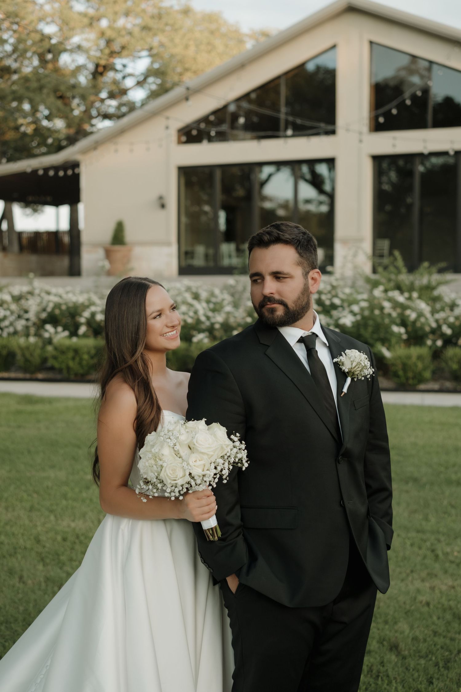 Bride in white strapless gown applies perfume in elegant room with geometric wall details.