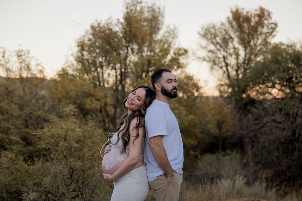 Romantic couple embraces in golden sunlight during outdoor photo session surrounded by autumn trees.