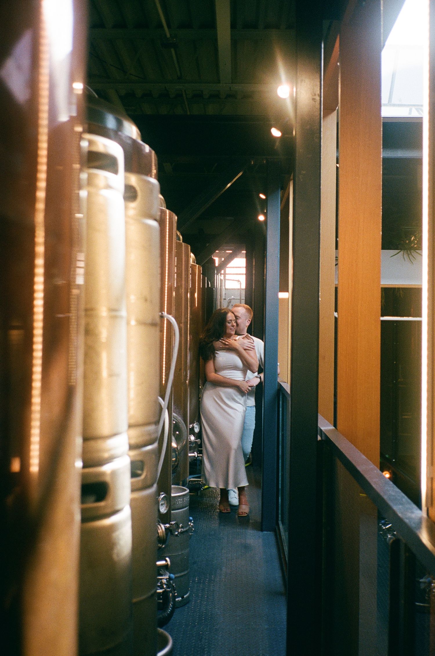 Couple embraces on steps of grand neoclassical building with towering columns. Captured on 35mm film during engagement photoshoot by Aliza