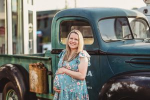 A maternity portrait next to a vintage blue pickup truck.