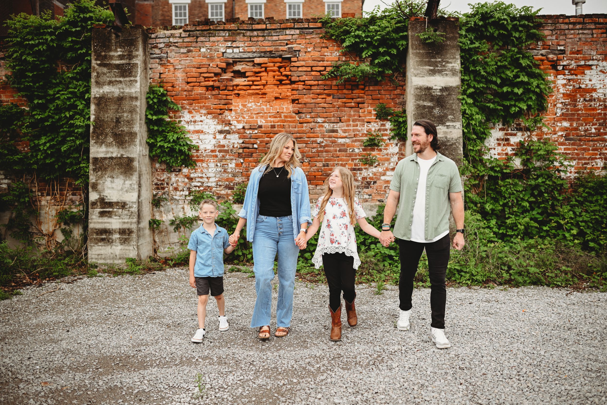 Group photos taken in front of a historic red brick wall with ivy and architectural details.