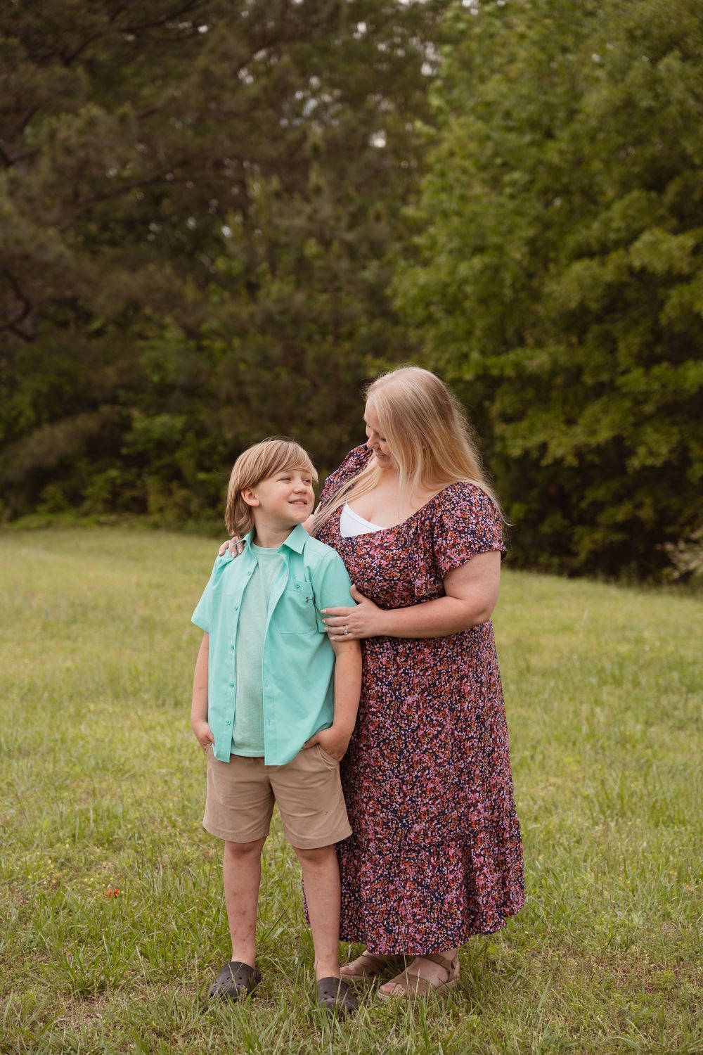 Mother and child share a tender moment while posing in a grassy field.