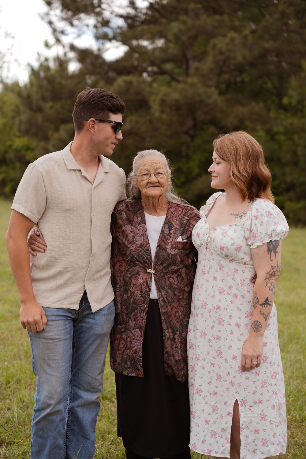 Three generations pose together outdoors wearing casual spring attire.