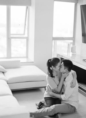 Black and white photo of couple sharing intimate moment on floor of bright modern apartment.
