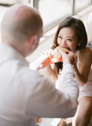 Man feeding woman a sandwich during a casual NYC engagement photo session indoors.