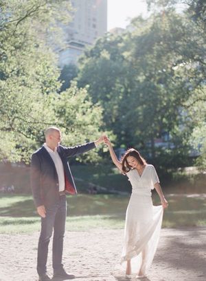 Couple dancing outdoors in Central Park with man spinning woman in white dress.