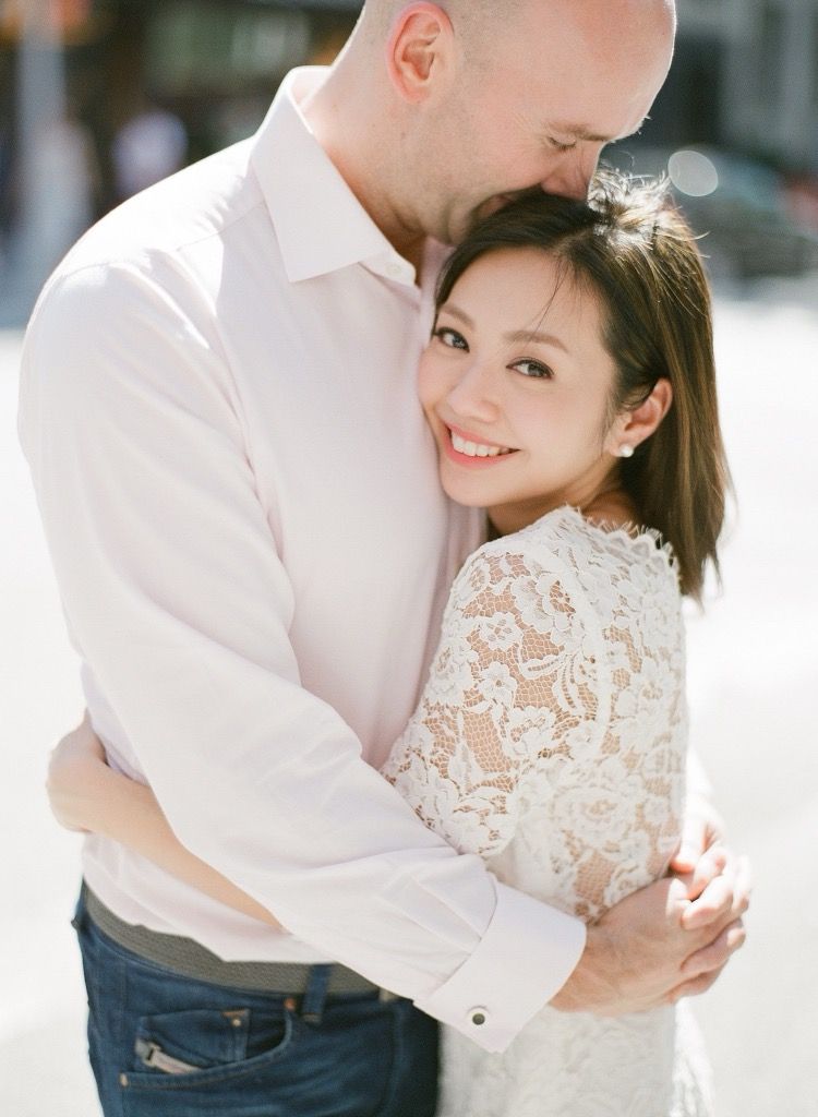 Couple sharing a romantic embrace on a sunny city street during engagement photos.