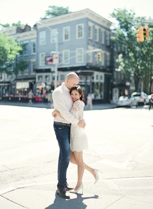 Couple embracing on a sunny city street corner during an engagement photo session.