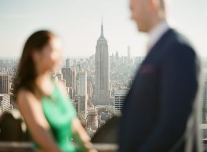 Couple with Empire State Building skyline backdrop in New York City engagement photo.