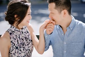 Romantic couple sharing tender moment as man kisses woman's hand during outdoor engagement photo session.