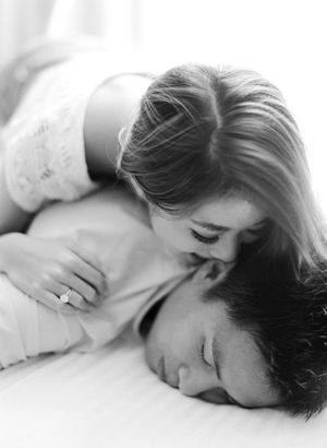 Romantic black and white intimate portrait of couple lying together, showcasing elegant diamond engagement ring.