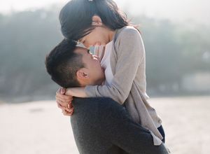 Couple sharing a tender embrace on a misty beach, woman lifted off the ground.