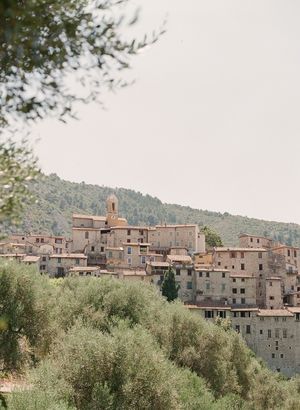 Scenic view of a historic hilltop village surrounded by olive trees and greenery.
