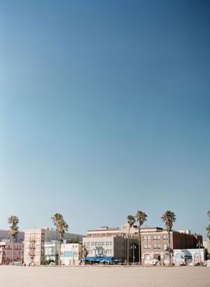 Colorful beachfront buildings with palm trees under a clear blue sky at Venice Beach.