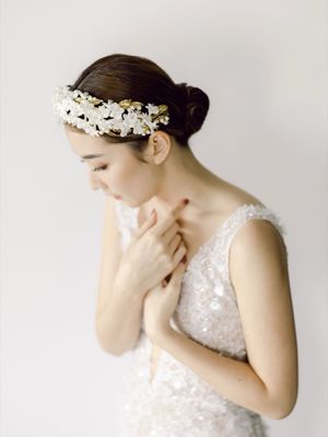 Elegant bride wearing a floral crown and sequined gown with hands clasped at her chest.