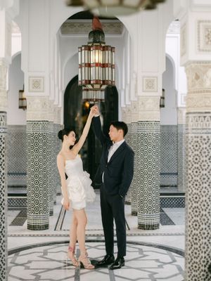 Bride and groom dance beneath a decorative Moroccan lantern surrounded by intricate mosaic tiled columns.