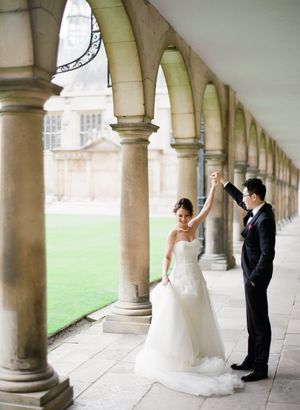 Bride and groom dance under stone archways at a classical European university courtyard wedding venue.