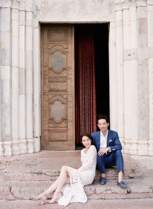 Couple sitting on steps of an ornate stone church doorway in a charming European destination.