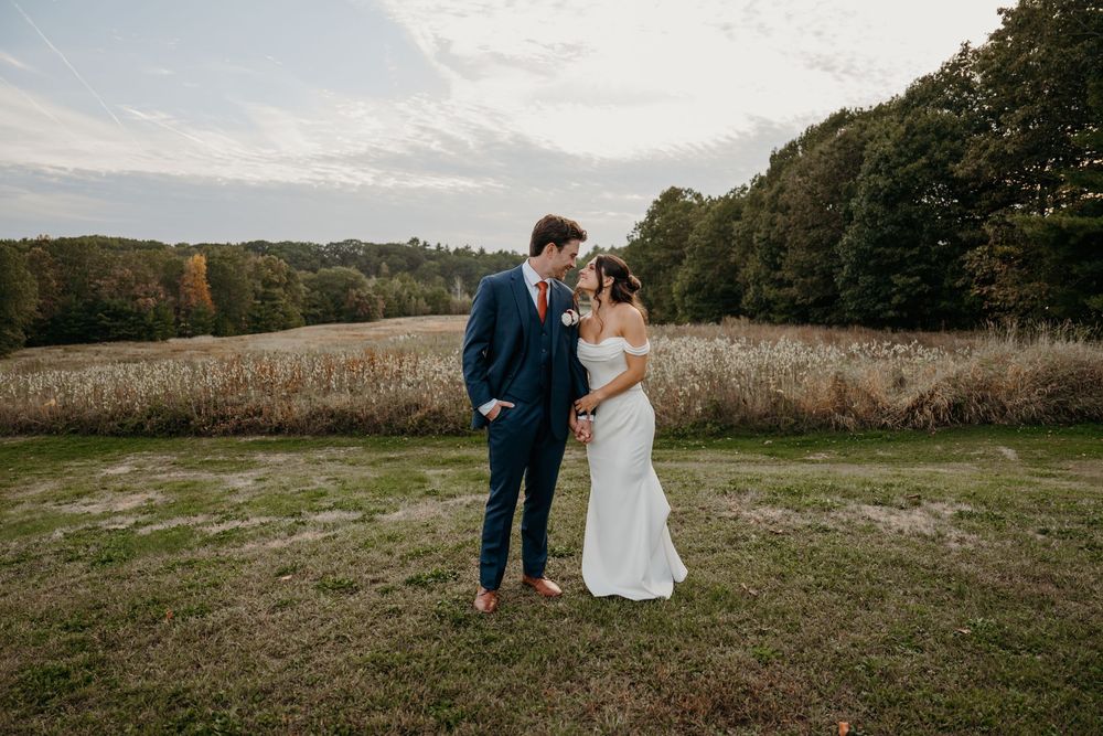 A couple shares a romantic moment in an autumn field at sunset as their silhouettes stand against the golden light.