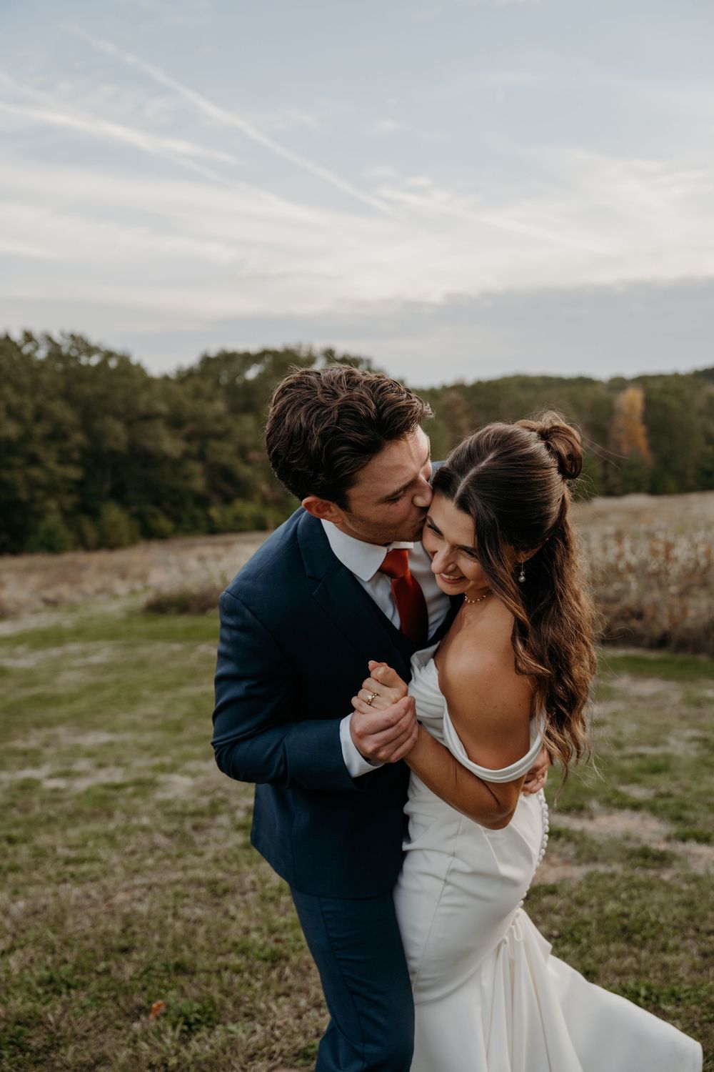 A romantic wedding photoshoot in a scenic field during golden hour.