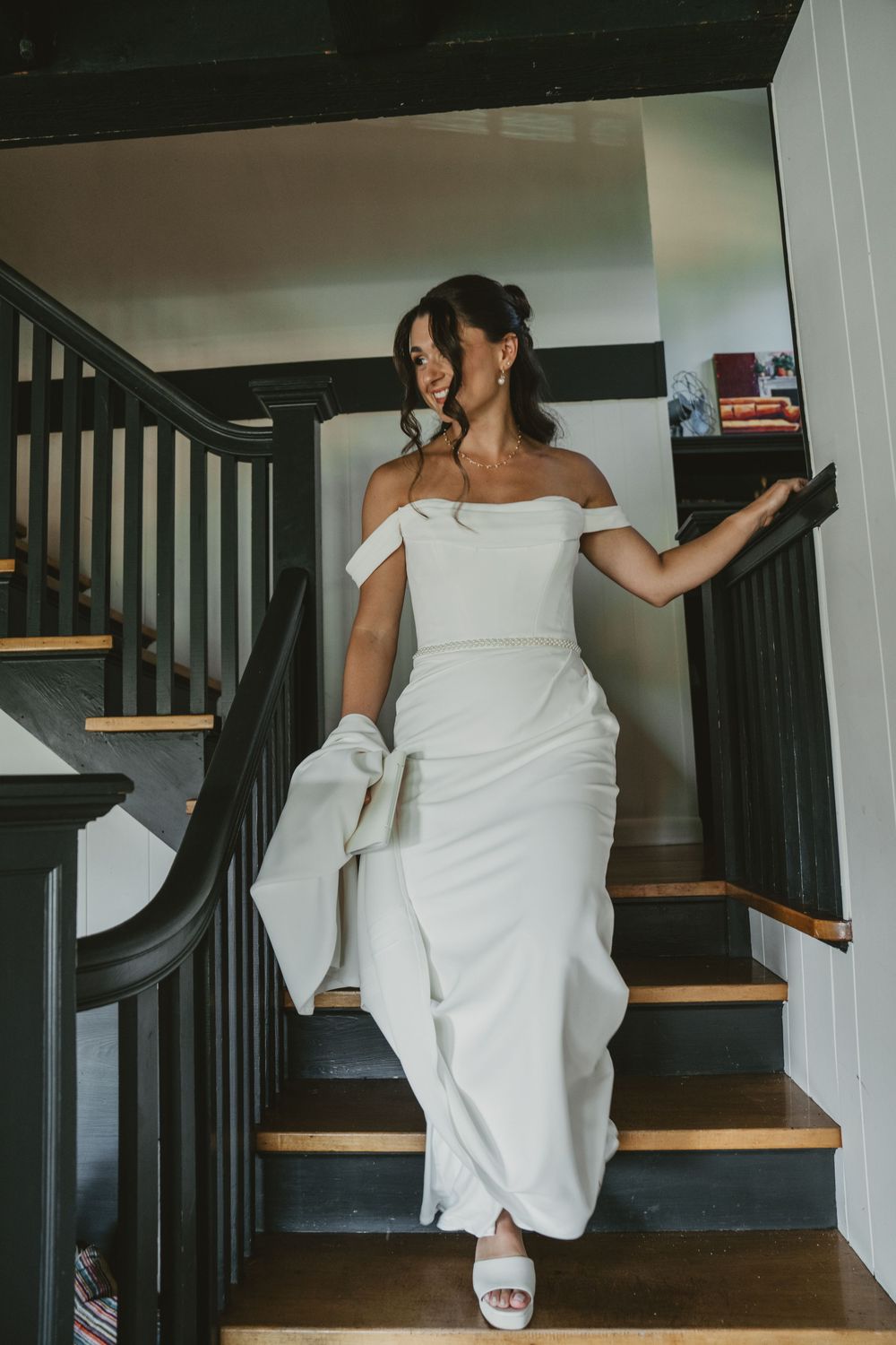 A sequence showing someone in a white dress descending wooden stairs gracefully.