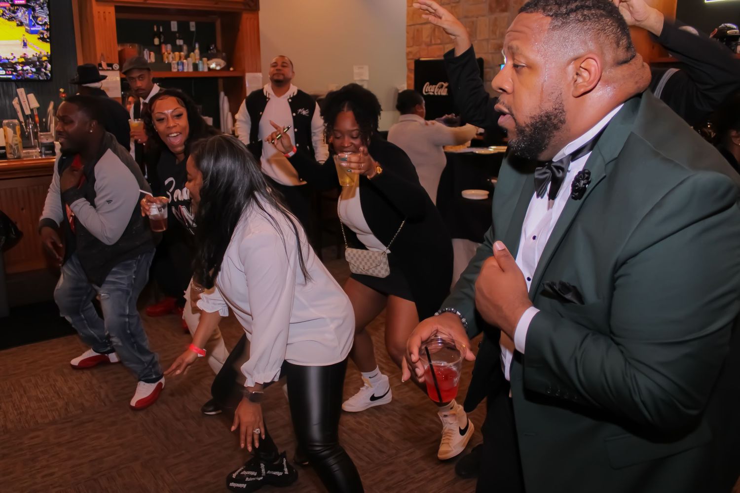 People dancing and celebrating at an event with a DJ performing in formal attire.