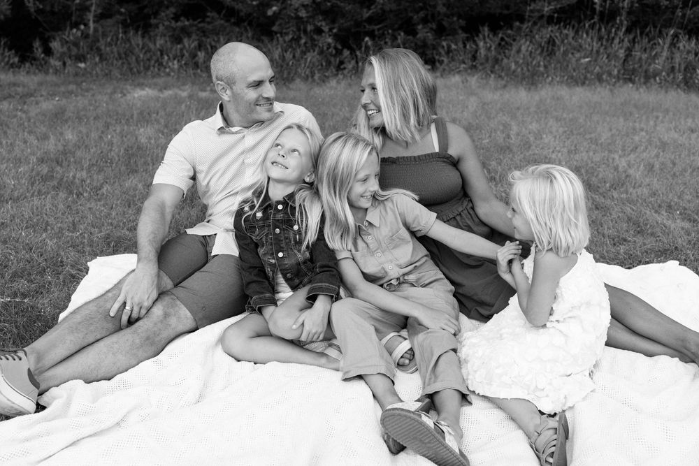 Family lying together on grass in black and white candid photography series.