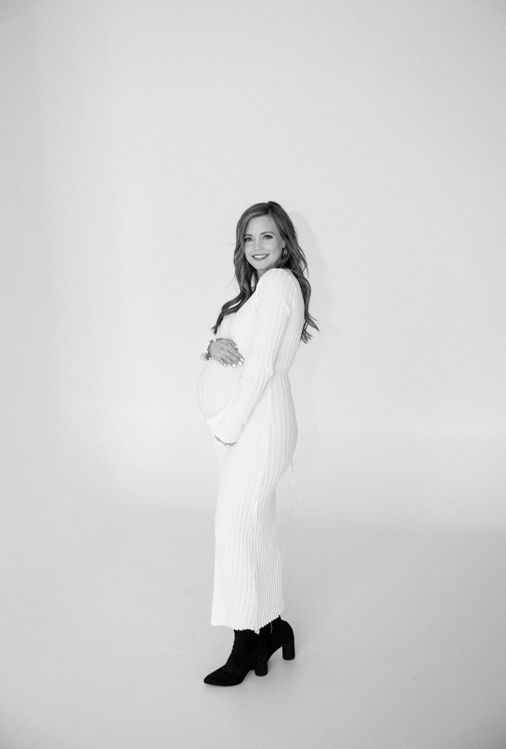 Woman in a white sweater dress poses against a light background in various artistic angles.