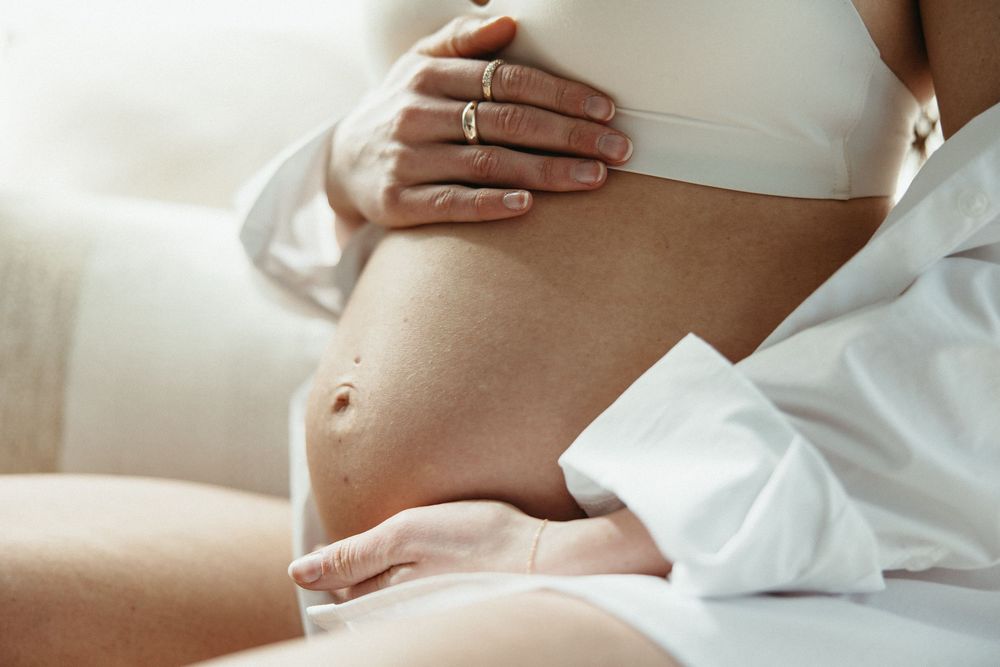 Series of intimate maternity photos focusing on pregnant belly in white clothing.