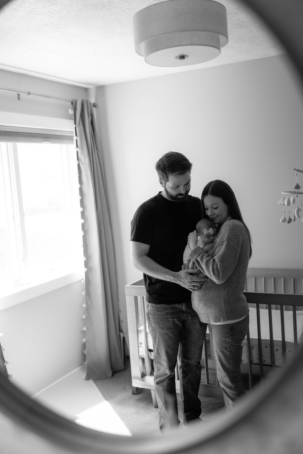 A series of black and white images showing tender moments between a couple in a nursery room.
