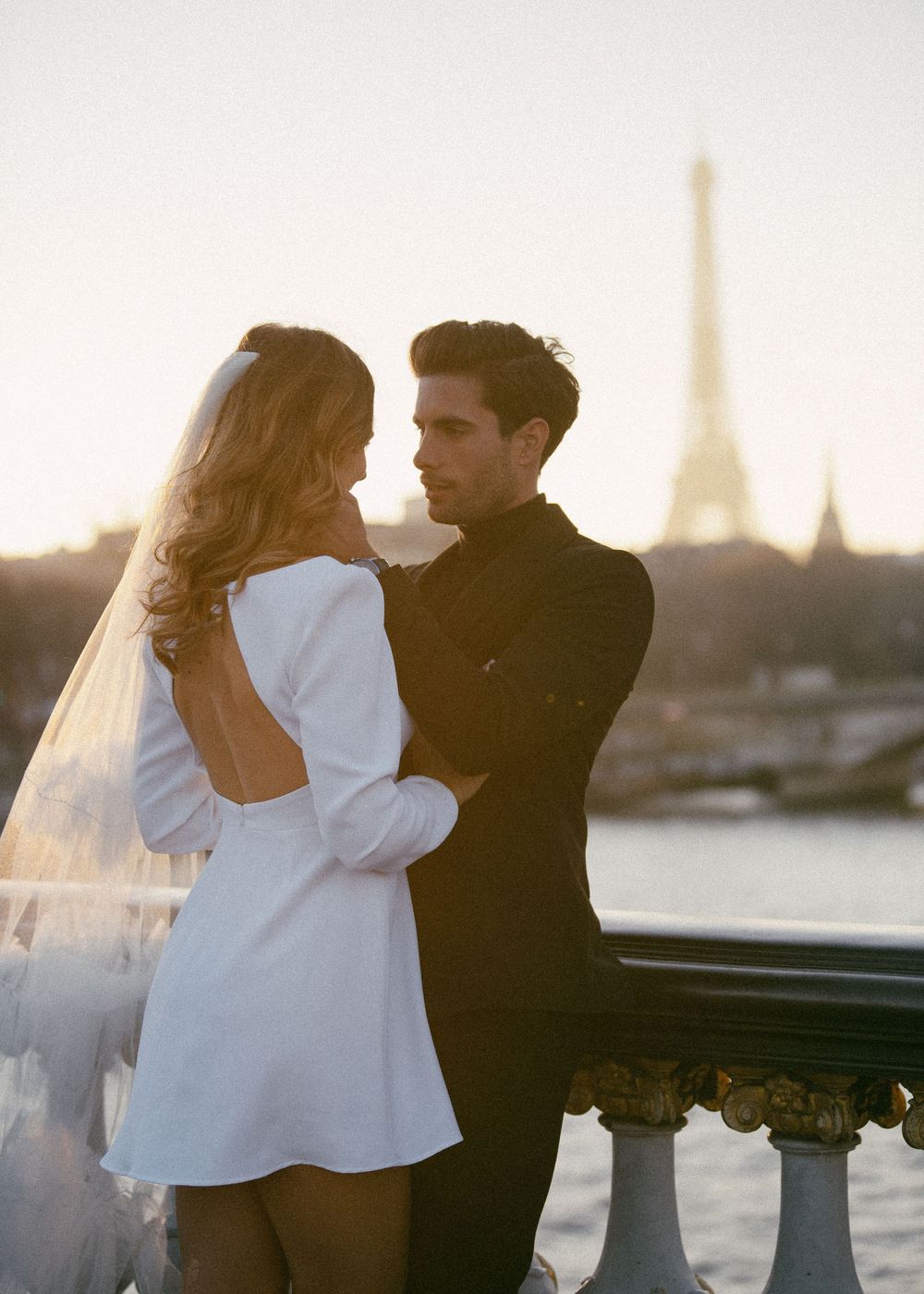 Romantic couple embraces with Eiffel Tower in background during sunset in Paris.