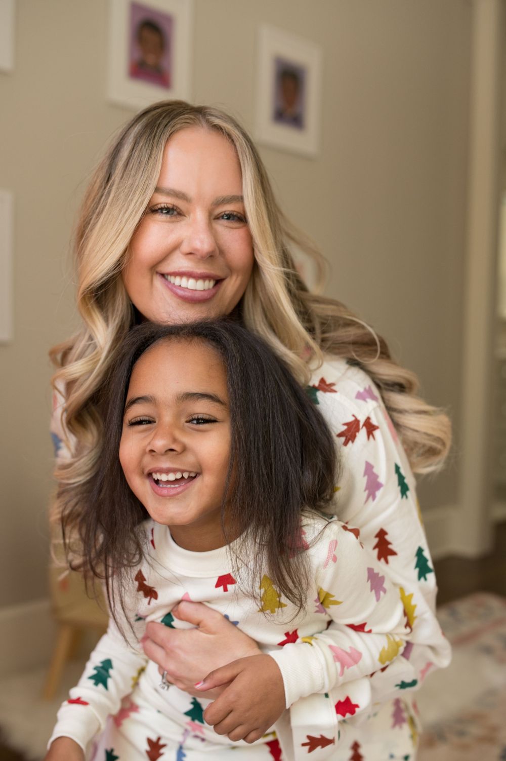 Mother and child share a joyful moment wearing matching Christmas tree patterned sweaters in a cozy home setting.