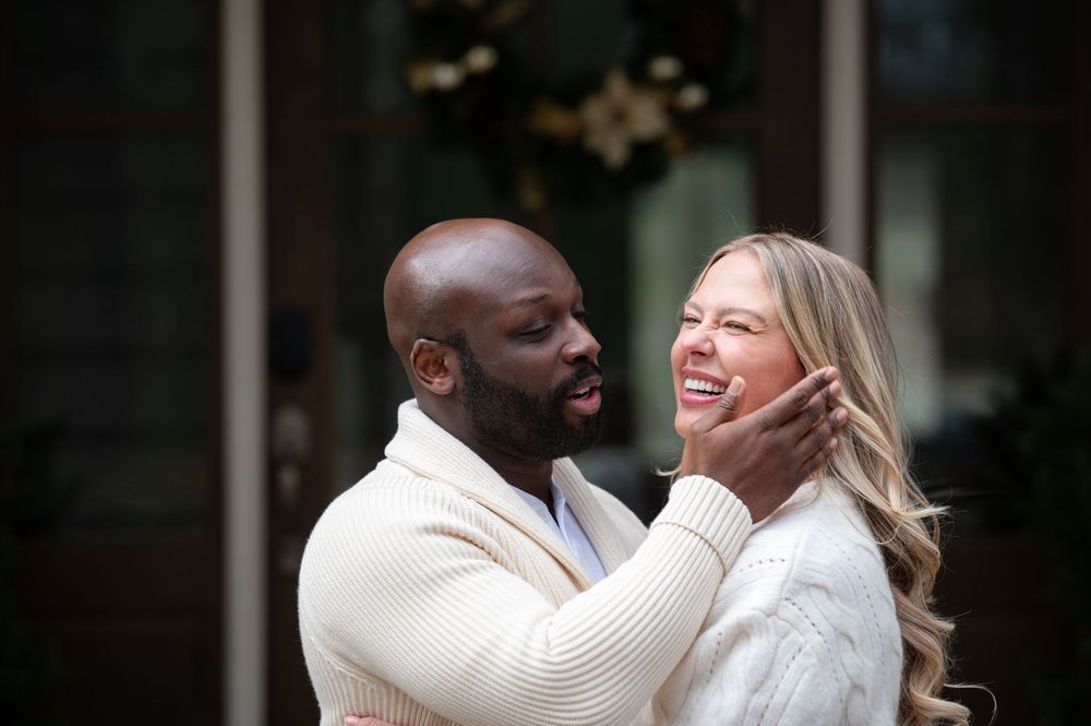A loving couple shares a joyful moment together while wearing cozy white sweaters during an outdoor photo session.