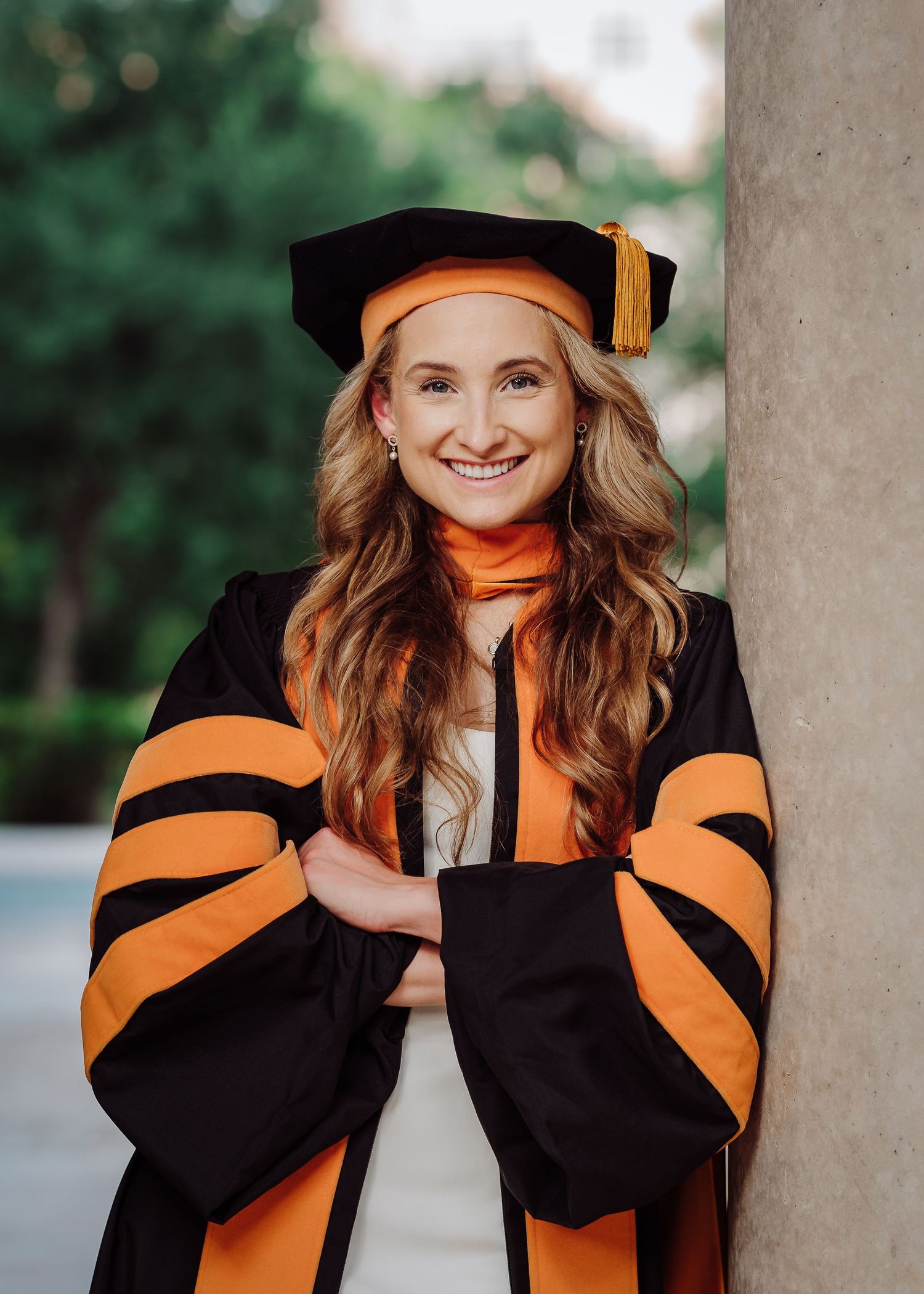 woman wearing a graduation cap sitting next to holistic nursing college books