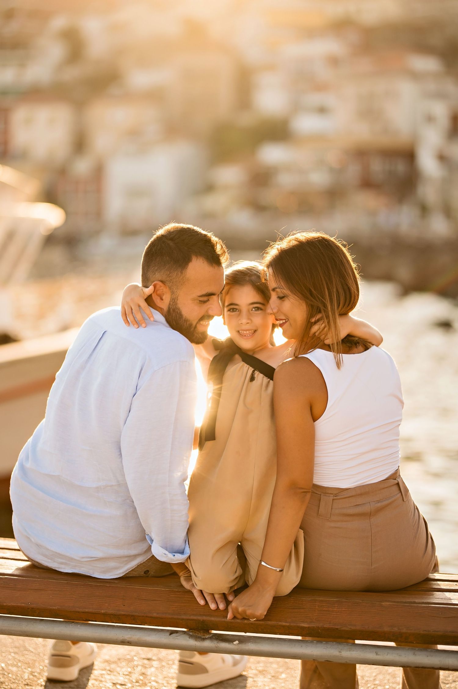 Three friends share an intimate moment together while sitting on a ledge at golden hour.