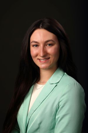 Professional portrait of person wearing mint green blazer and cream top.