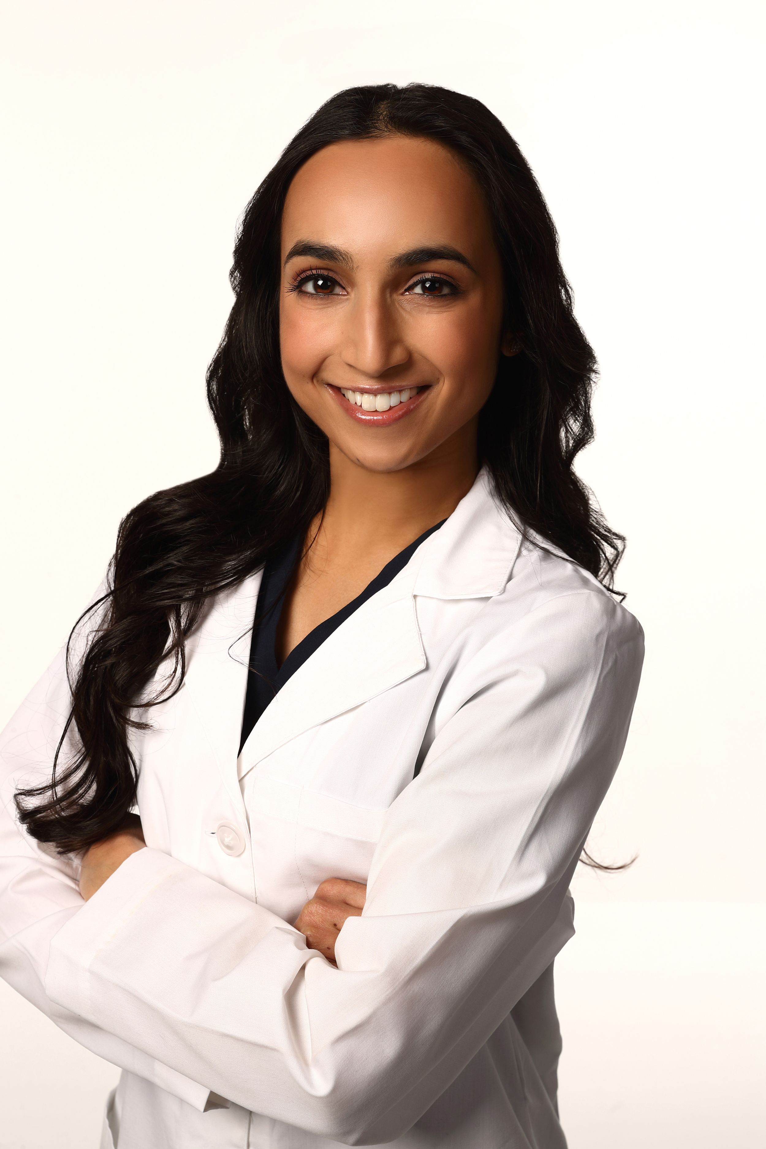 A healthcare professional in a white lab coat stands confidently against a white background.