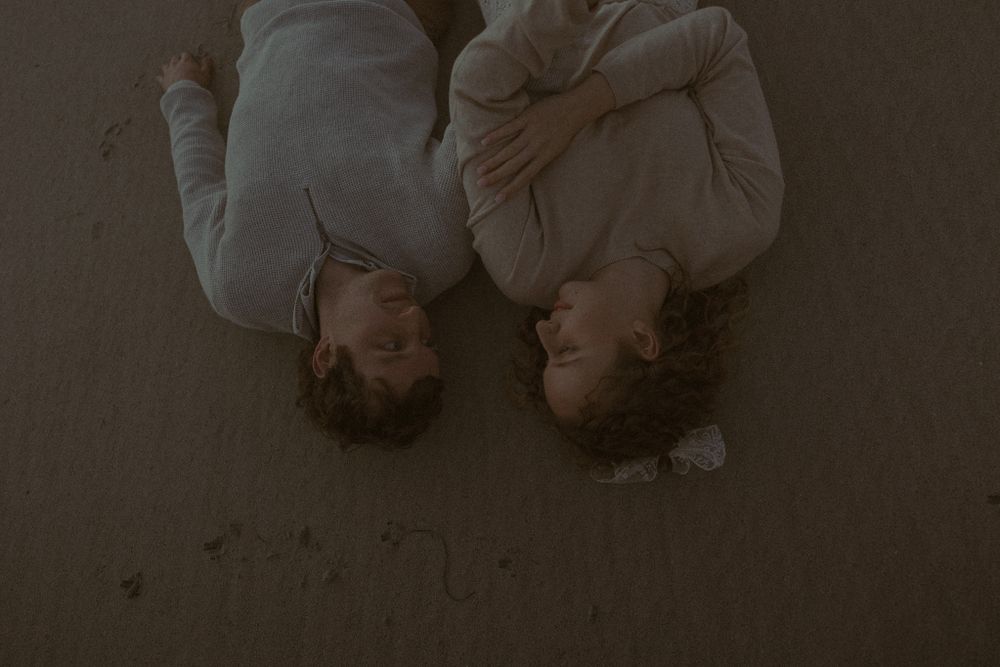 Couple lying on sand creating romantic beach photography.