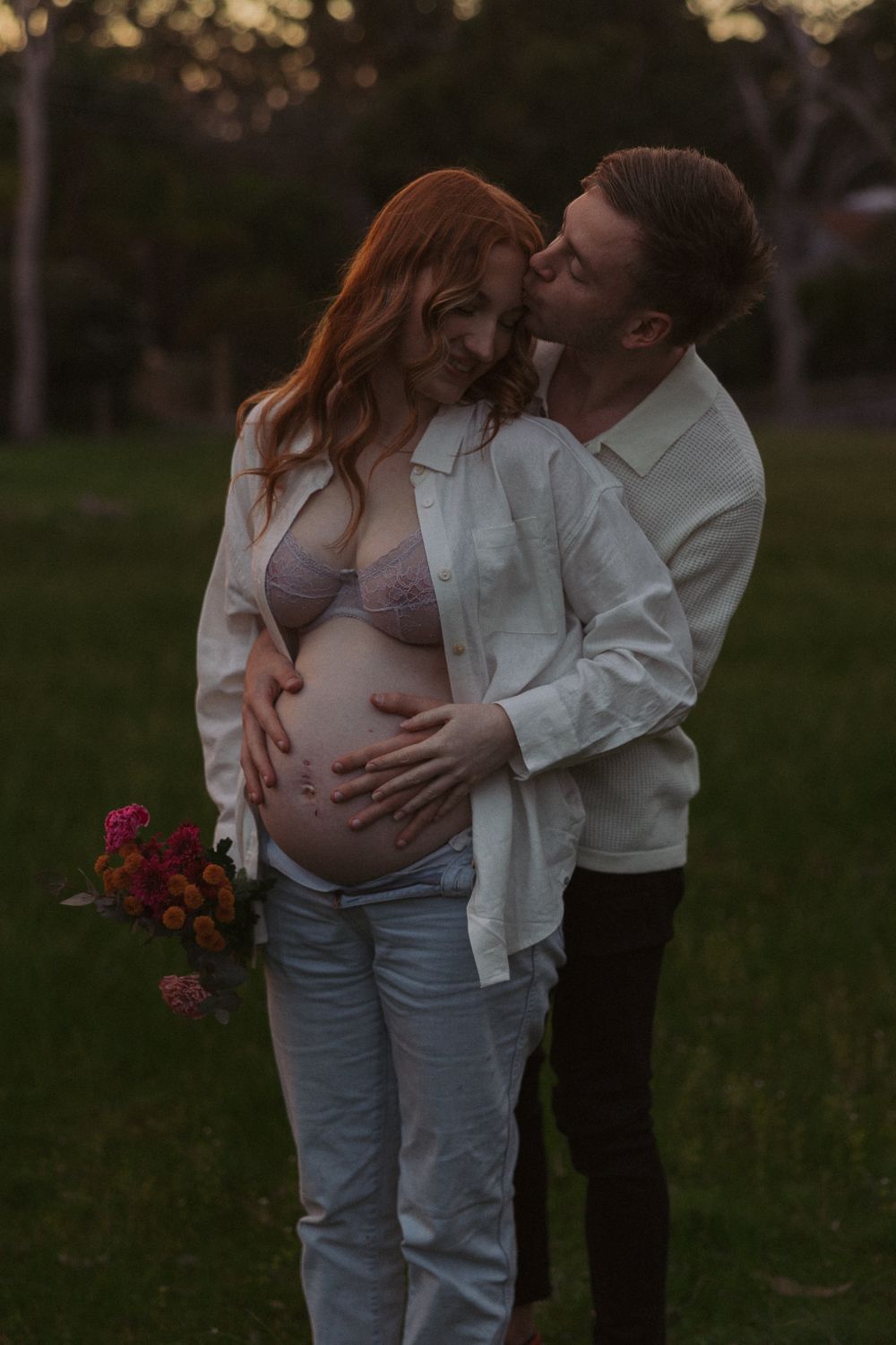 An intimate maternity photoshoot in a field during golden hour.