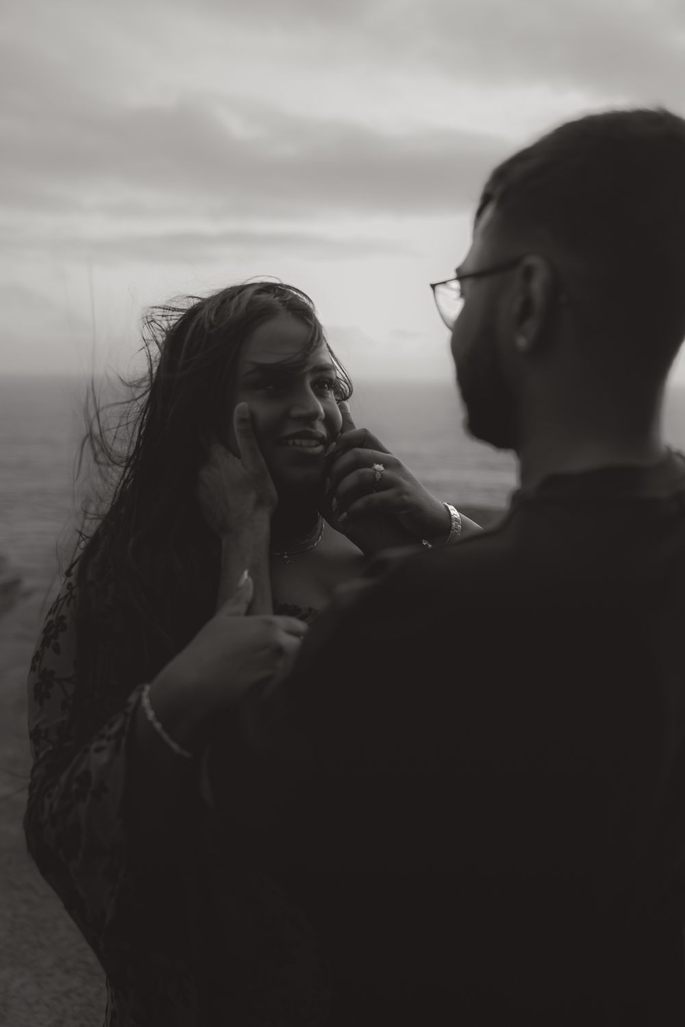 Silhouettes of a couple sharing an intimate moment against a moody sky.