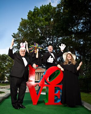 Four people in formal wear celebrating beside LOVE sculpture outdoors.