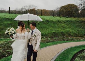 A romantic outdoor wedding photoshoot on a winding path surrounded by lush green landscapes and autumn foliage.
