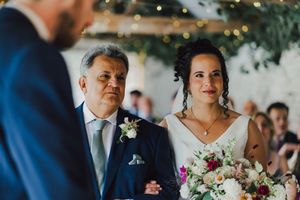 Wedding couple showing affection during outdoor ceremony while guests look on with smiles and emotions.