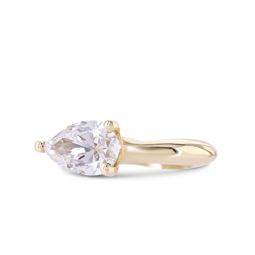 A delicate gold ring with a pear-shaped diamond solitaire stone set in a minimalist prong setting.