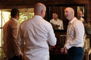 Groomsmen talking in front of mirror.